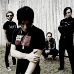 Promovalokuva neljän hengen miehittämästä Apoptygma Berzerk -bändistä. Kuvassa neljä mustiin pukeutunutta miestä, jotka seisovat valkoisen lautaseinän edustalla ulkoilmassa. Osa miehistä on pukeutunut goottityylisiin vaatteisiin, osalla rokkarim