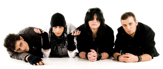 Valokuva The Pussybats -bändin neljästä miesjäsenestä, jotka makaavat valkoista taustaa vasten rivissä. Kuvan jäsenet pukeutuneet pääosin mustiin vaatteisiin. Osalla mustat sormikkaat tai kynsikkäät käsissään.