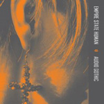 Empire State Humanin albumilla "Audio Gothic" näkyy lähikuva ihmisen korvasta, jossa roikkuu jonkinlainen koristeellinen ristiä muistuttava koru. Ihmisellä puolipitkät kellertävät hiukset. Kuva on kellertävä ja sen oikeassa laidassa tummanharmaa