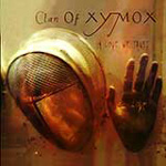Clan Of Xymoxin "In Love We Trust" -albumin etukannessa näkyy jonkinlainen teräsnaamariin pukeutunut hahmo seisomassa allapäin vierellään kätensä. Kuvan yläosassa yhtyeen logo ja sen alla pienemmällä präntillä albumin nimi. Kuvan väriskaala o