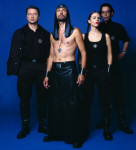 Laibach-bändin promokuva, jossa kolme miestä ja yksi nainen seisovat kirkkaan sinistä taustaa vaten. Keulahahmolla ei ole paitaa yllään.