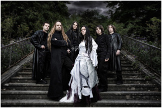 Ryhmäkuva Erben der Schöpfungin goottilaumasta, johon kuuluu viisi mustiin pukeutunutta goottimiestä ja heidän edessään keskimmäisenä valkoiseen häämekonkaltaiseen pukeutunut mustahiuksinen goottinainen. Kuvassa taustalla goottihenkiset portaat.