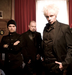 Goottibändi The Beauty of Geminan kokoonpanoon kuuluvat goottimiehet mustiin pukeutuneena huoneessa, jonka ikkuna antaa vaaleaa valoa. Ikkunan laidoilla punaiset raskaat verhot. Kuvassa näkyvistä miehistä oikeanpuleisella on valkoinen tukka.