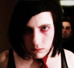 Valokuva We Are Now Awake -bändin kahdesta miesmuusikosta, joista toinen on etummaisen miehen takana kauempana samalla kun emolta näyttävät etualalla oleva mies murjottaa.