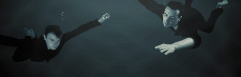 Liquid Divine -bändin jäsenet, eli kaksi miestä, veden alla upoksissa. Vesi on tummaa, miehillä mustat vaatteet ja lyhyet mustat hiukset.