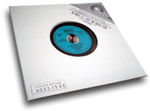 Valkoinen tausta ja sitä vasten LP-levyn paperikotelo, jonka keskellä aukko. Siitä näkyy sininen vinyylilevyn etiketti.