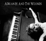 Mustaharmaa valokuva pianon päällä kädet sivuillaan makaavasta nuoresta naisesta. Kuvan yläosassa lukee valkoisella Adrian H And The Wounds.