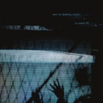 Hämärä ja epätarkka valokuva verkkoaidasta, jota vasten ihmisten käsiä. Kuvan yläosa on tumma, lähes musta ja alaosa sinisävyinen.