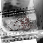 "Terrorized Trax Vol. 1 (2008–2010)" -kokoelman etukannessa lähes harmaasävyinen valokuva jonkinlaisesta kivestä, jossa punaisia tarhoja.