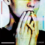 Valokuva miehen kasvoista ja mies pitämässä käsiään suunsa edessä. Kuva on ylivalottunut ja väritykseltään nuhjuinen.