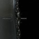 Kuvassa mustaa ja harmaata, jonka keskellä kulkee pystysuuntaisesti kupliva juova.