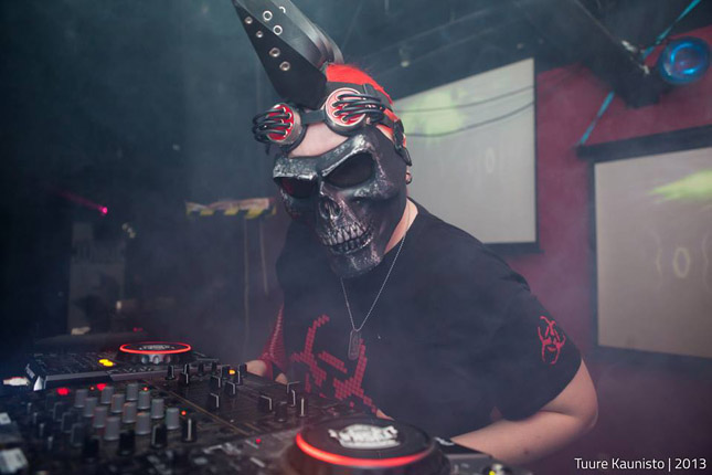 Valokuva DJ emanonista. Kuvassa mikseripöydän äärellä henkilö, jolla pääkallonaamari kasvojen edessä.