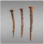 Vaaleanharmaa tausta, jota vasten rivissä kolme erilaista ruostunutta naulaa.