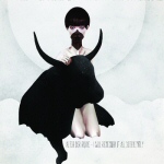 Vaaleanharmaata ja -sinistä taustaa vasten valokuva suuripäisestä ihmisestä, jolla omituisesti laskostuva musta leninki.