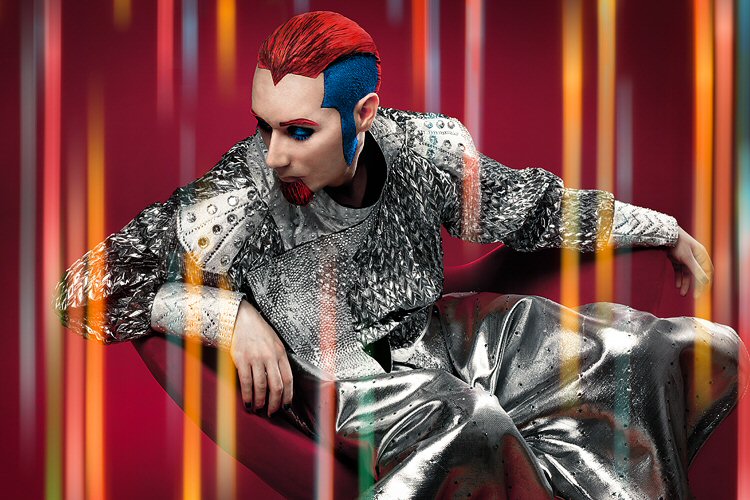 Kuvassa Digitalis Purpurean taustavoima kuvattuna punaista taustaa vasten futuristisessa hopeanvärisessä asussaan.