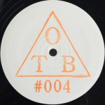 Mustaa taustaa vasten valkoinen rinkula, jonka keskelle sijoitettu oranssilla värillä kolmio ja sen sisälle kirjaimet OTB.