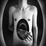 Harmaasävyinen piirros alastoman ihmisen vartalosta, jonka vatsassa on suuri ovaali rikä ja josta tulee käsi läpi.