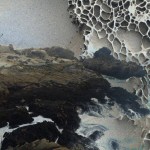 Maalaus myrskyävästä merestä oikealla puolen ja kivikosta vasemmalla. Yläooikealal hunajakennomaista röpöä.