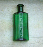 Vihreästä lasista muovattu lasipullo vaaleaa taustaa vasten. Pullossa lukee valkoisessa etiketissä englanniksi 'Pigt to be taken'.