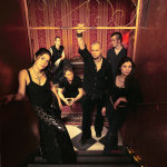 Schandmaul-yhtyeen kokonpano seisoo mustiin pukeutuneena punertavasävyisessä huoneessa, jonka seinät heijastavat himmeästi hahmojen piirteitä. Kuvassa etualalla kaksi naista, taka-alalla neljä miestä.