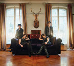 Ladytron-bändin nelipäinen naisjoukko, joka on majoittautunut ylelliseen sviittiin, jonka lattia kiiltävää tummaa puuta ja seinällä naisten takana sarvekkaan eläimen pää. Kuvassa takana kaksi suurta ikkunaa, joiden edustalla suuri musta sohva, j