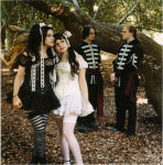 RazorBladeKisses-bändin kaksi naista ja kaksi miestä seisovat lehtipusta maahan tippuneiden elottomien lehtien päällä. Naiset etualalla, miehet takana. He ovat ulkosalla, metsässä. Naisilla mustat hiukset ja gothic lolita -vaatteet, miehillä koris