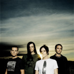 Apoptyhma Berzerkin valokuva, jossa näkyy koko nelihenkinen kokoonpano tummenevaa auringonlaskua vasten. Taivaalla paljon pilviä, miesten välistä hohkaa auringonsäteitä. Yhdellä hepulla pitkät musta letti, muilla lyhyet mustat hiukset.